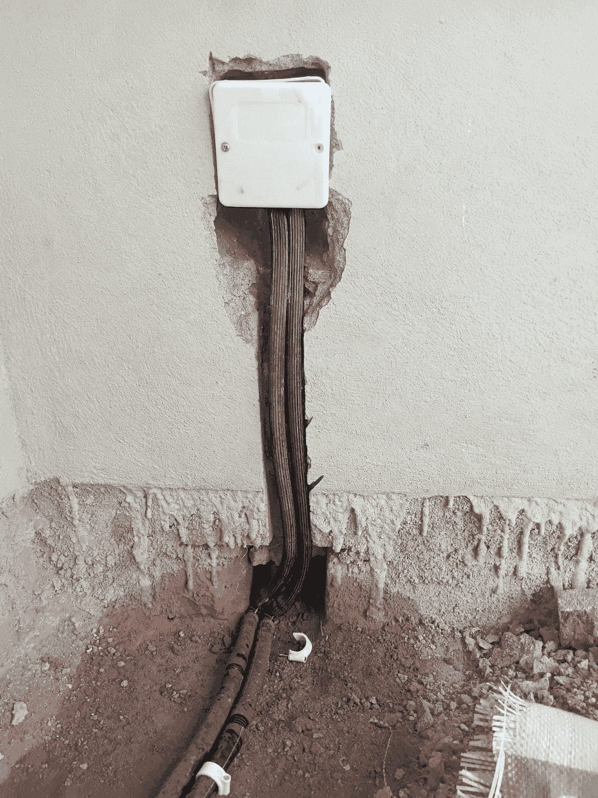 Close-up of an anti-termite injection point box on a wall with the pipes entering the floor below