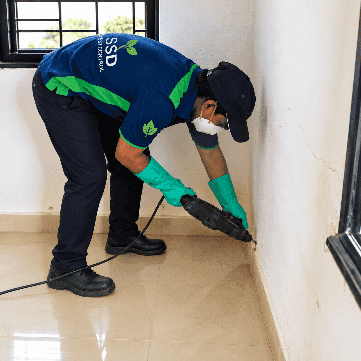 SSD technician drilling treatment holes along a skirting board for termite injection